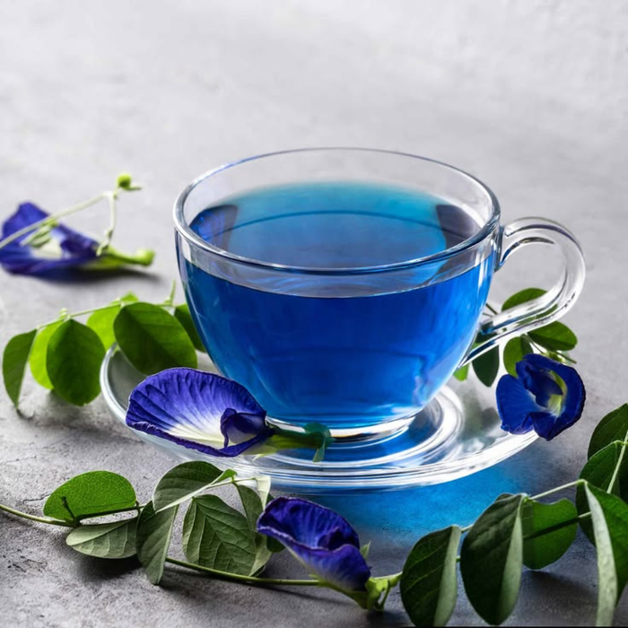 Butterfly pea flower tea brewing deep blue, next to a purple cup after adding lime